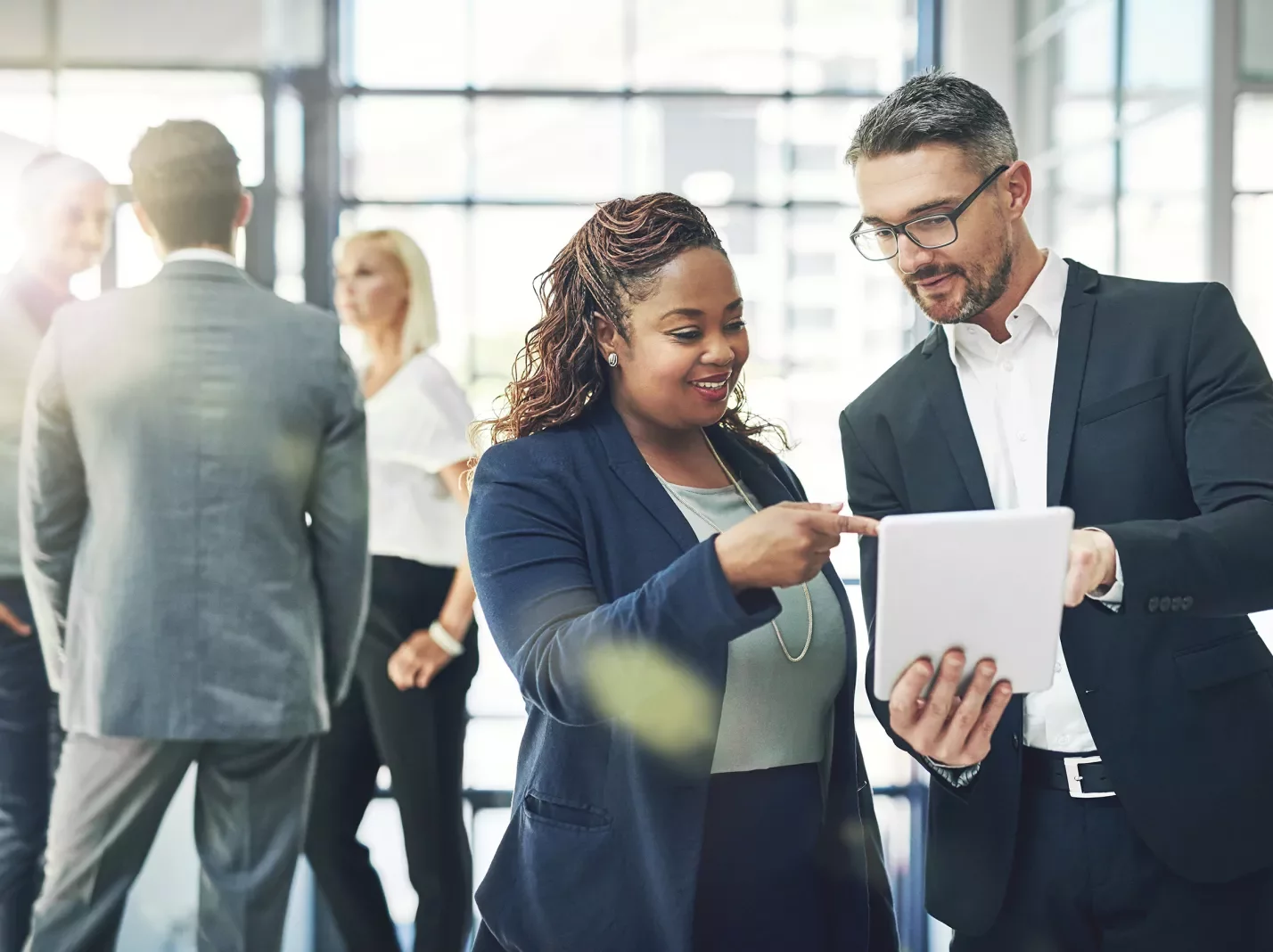 woman and man wearing suits and pointing at a document